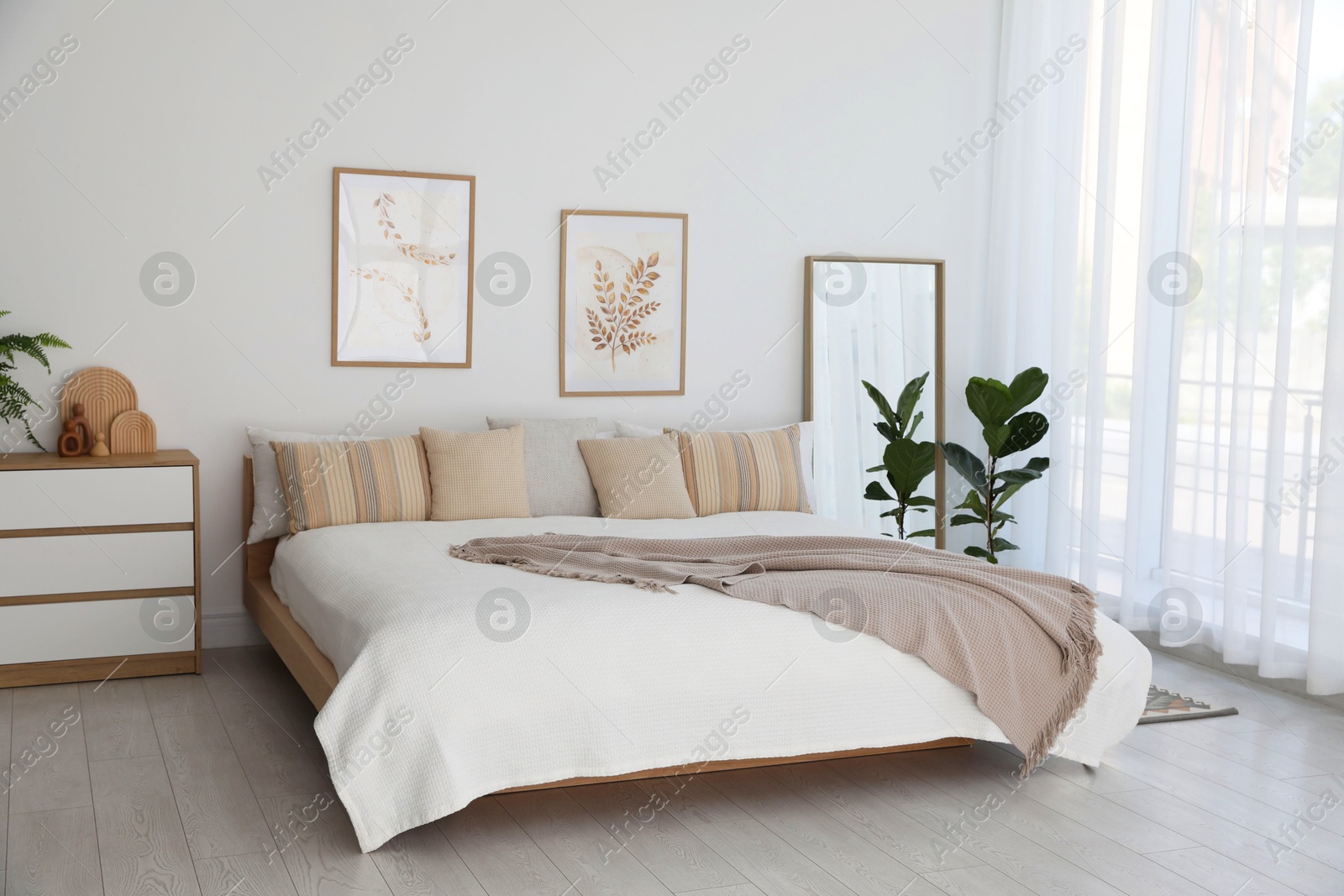 Photo of Large bed, houseplant and full-length mirror near window in room. Stylish bedroom interior