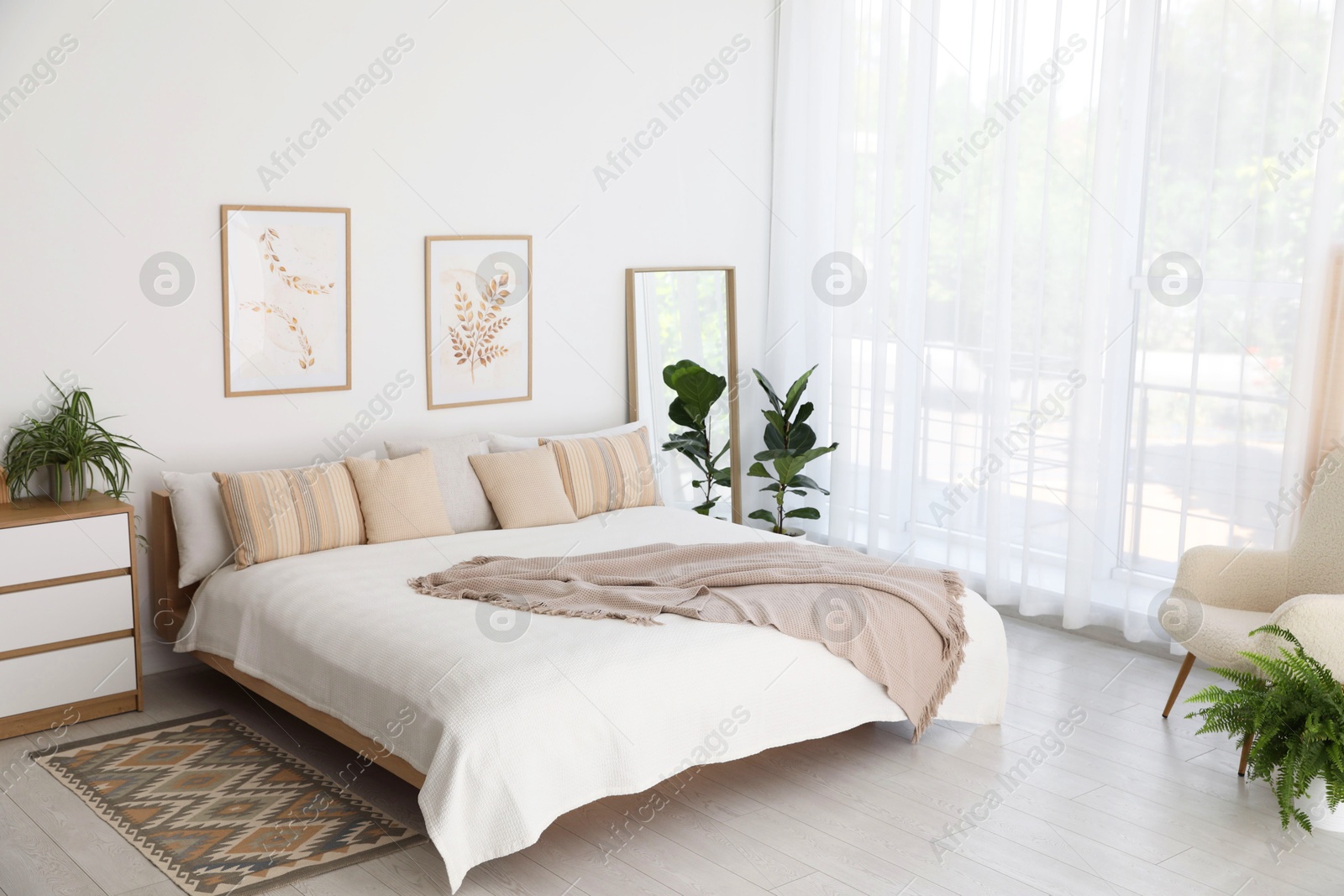 Photo of Large bed, houseplant and full-length mirror near window in room. Stylish bedroom interior