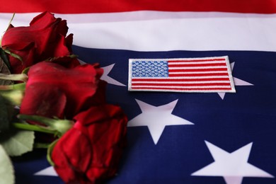 Photo of Veterans day. American army patch and rose flowers on USA flag, closeup