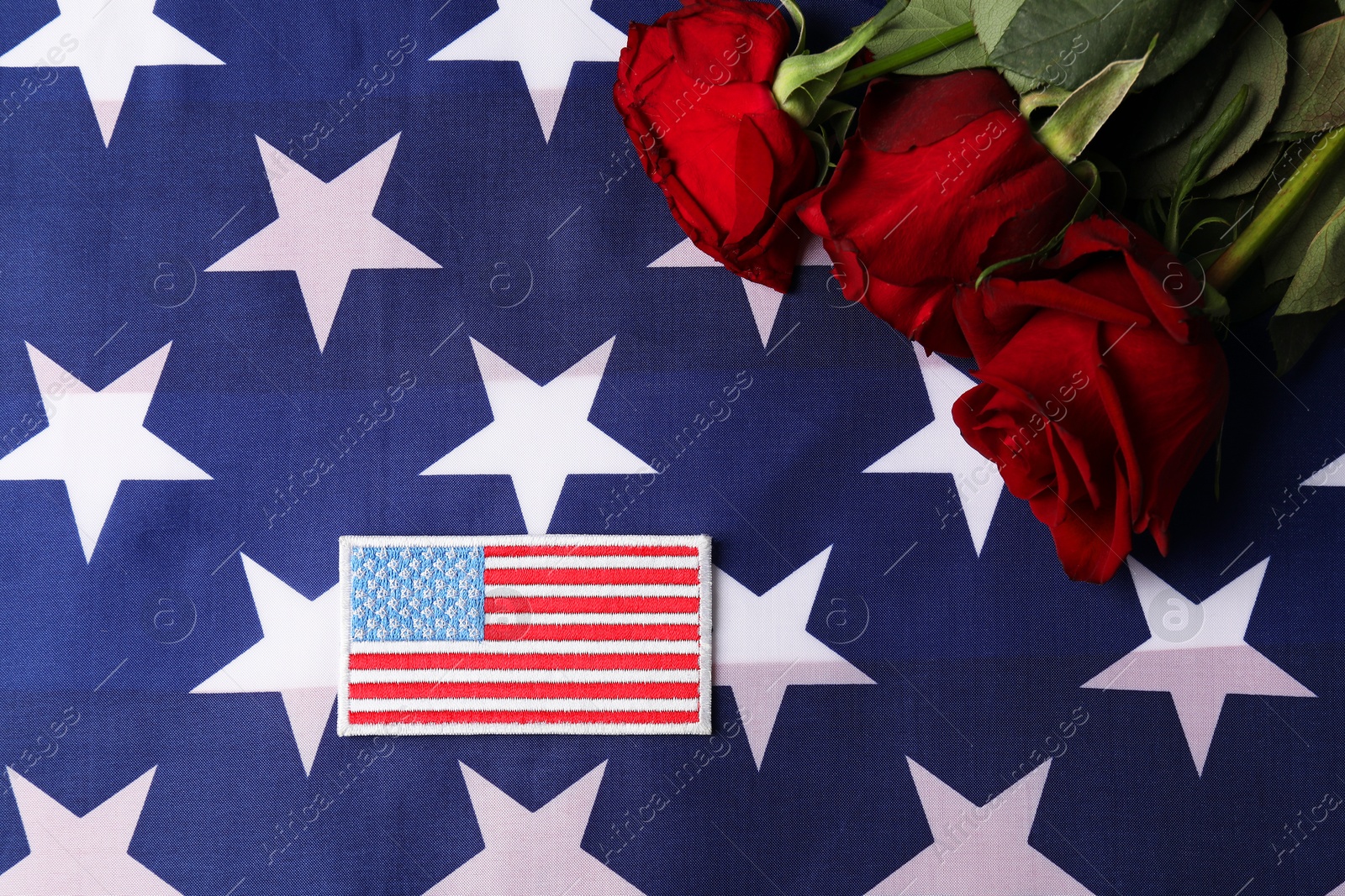 Photo of Veterans day. American army patch and rose flowers on USA flag, flat lay