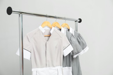 Photo of Maids' uniforms on clothing rack against grey background