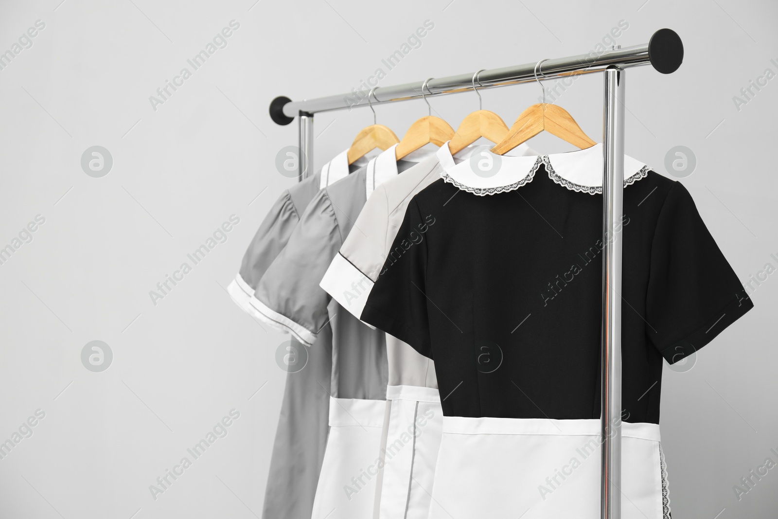 Photo of Maids' uniforms on clothing rack against grey background. Space for text