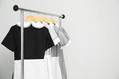 Photo of Maids' uniforms on clothing rack against grey background. Space for text