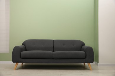 Photo of One stylish sofa near green wall indoors