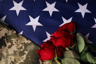 Photo of Veterans day. Rose flowers and military uniform on American flag, flat lay