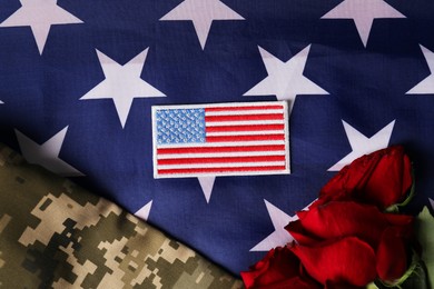 Photo of Veterans day. USA army patch, rose flowers and military uniform on American flag, flat lay