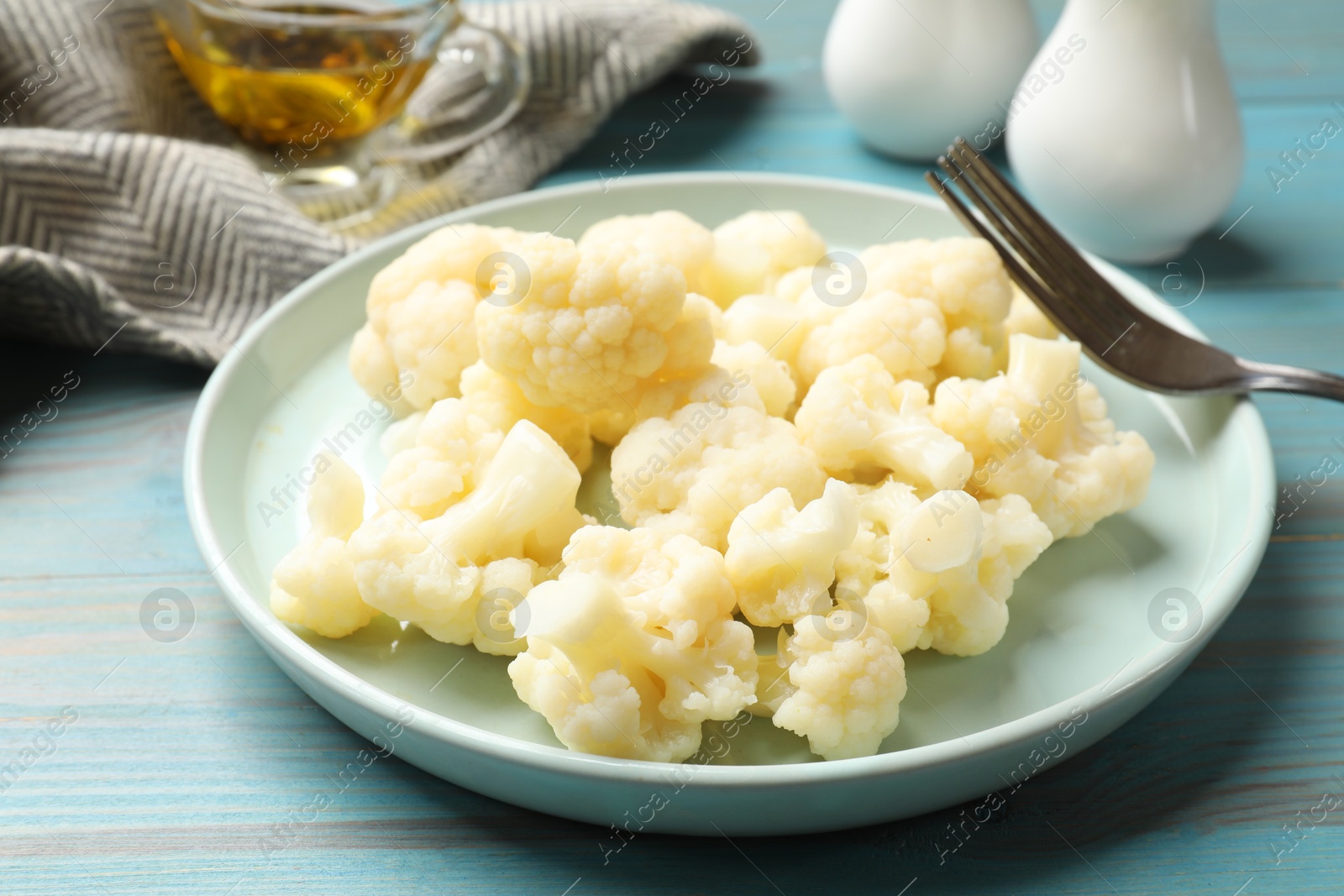 Photo of Tasty cooked cauliflower on light blue wooden table, closeup