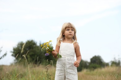 Photo of Cute little girl with flowers at meadow. Child enjoying beautiful nature