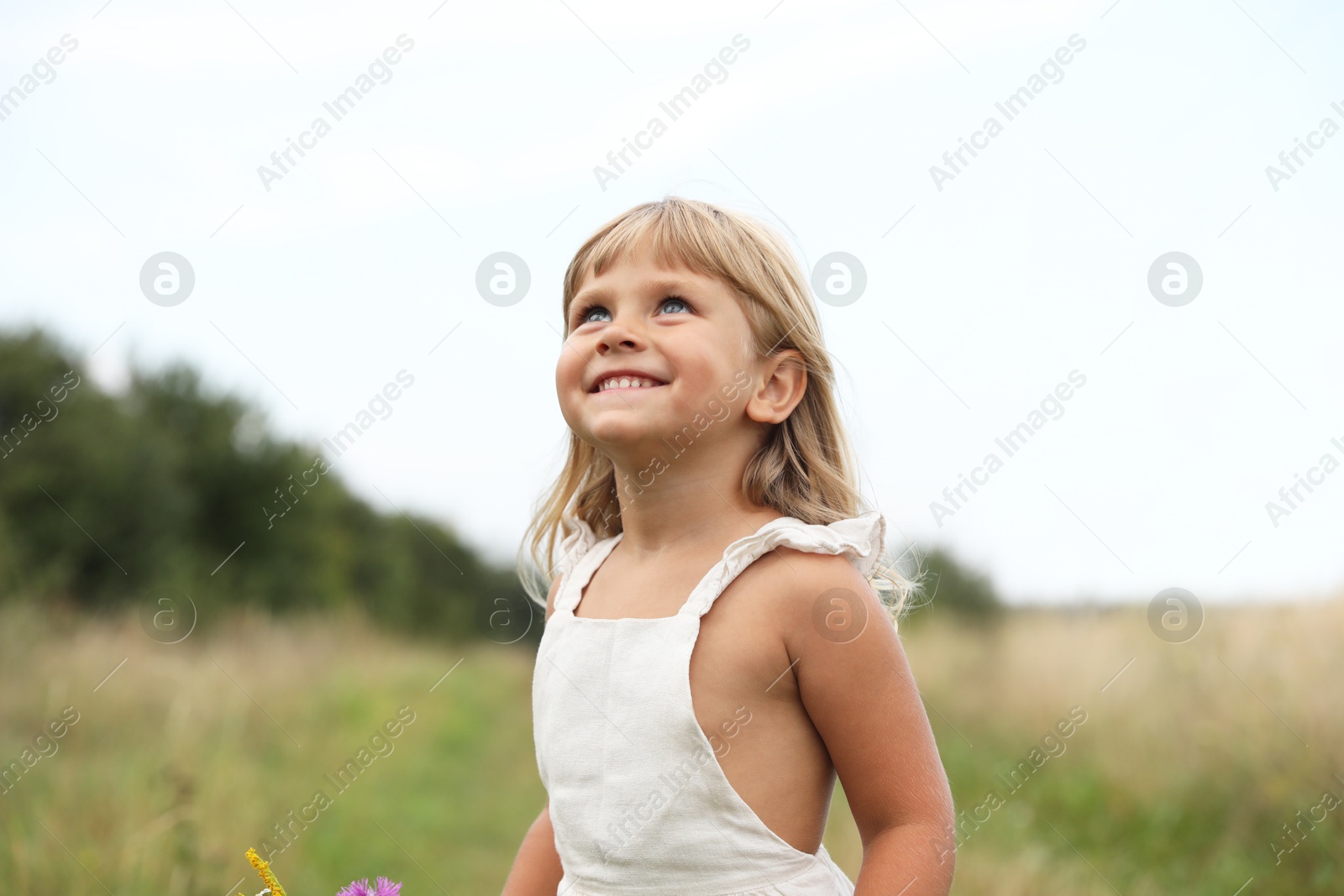 Photo of Cute little girl at meadow outdoors. Enjoying beautiful nature