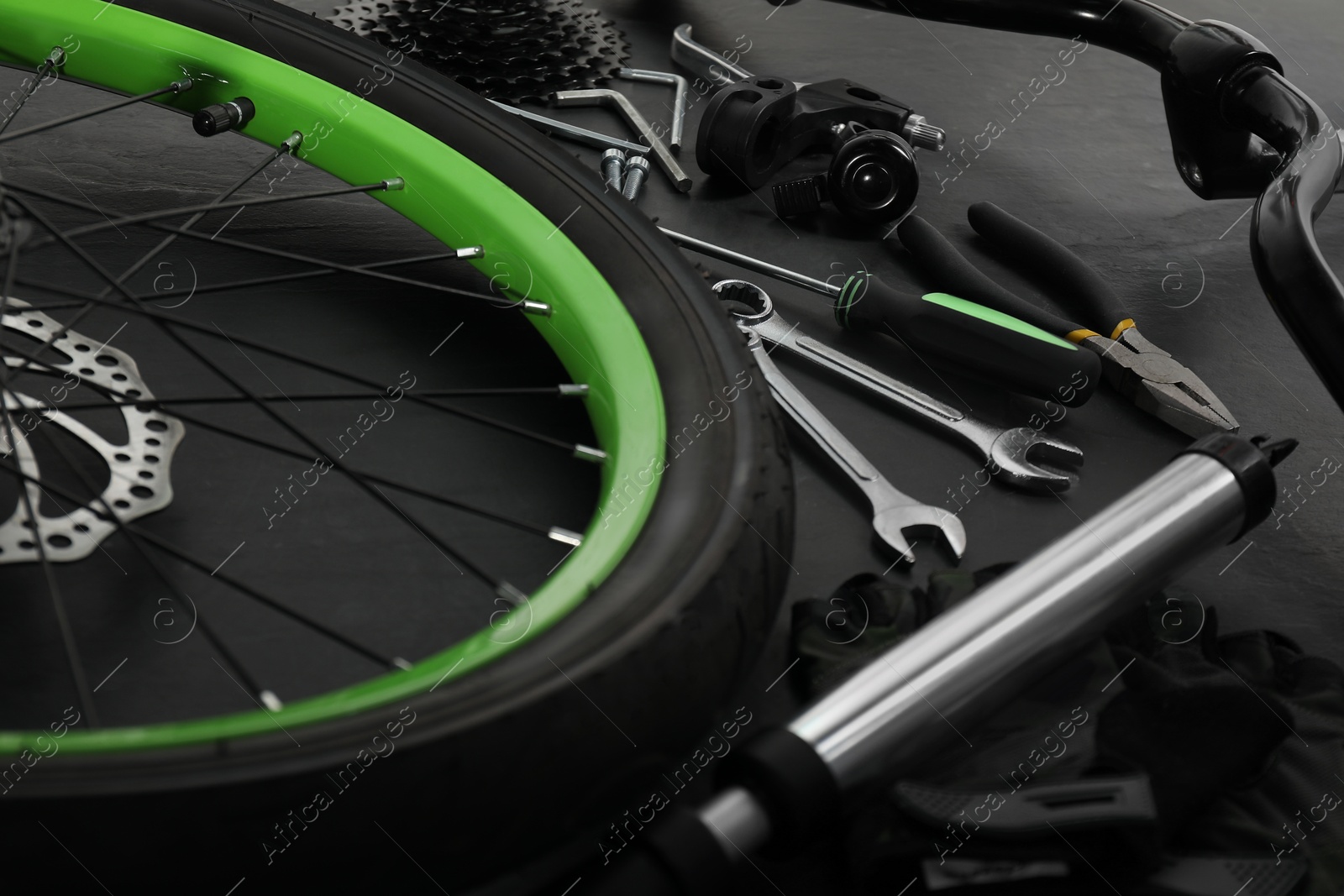 Photo of Parts of bicycle and tools on black background, closeup