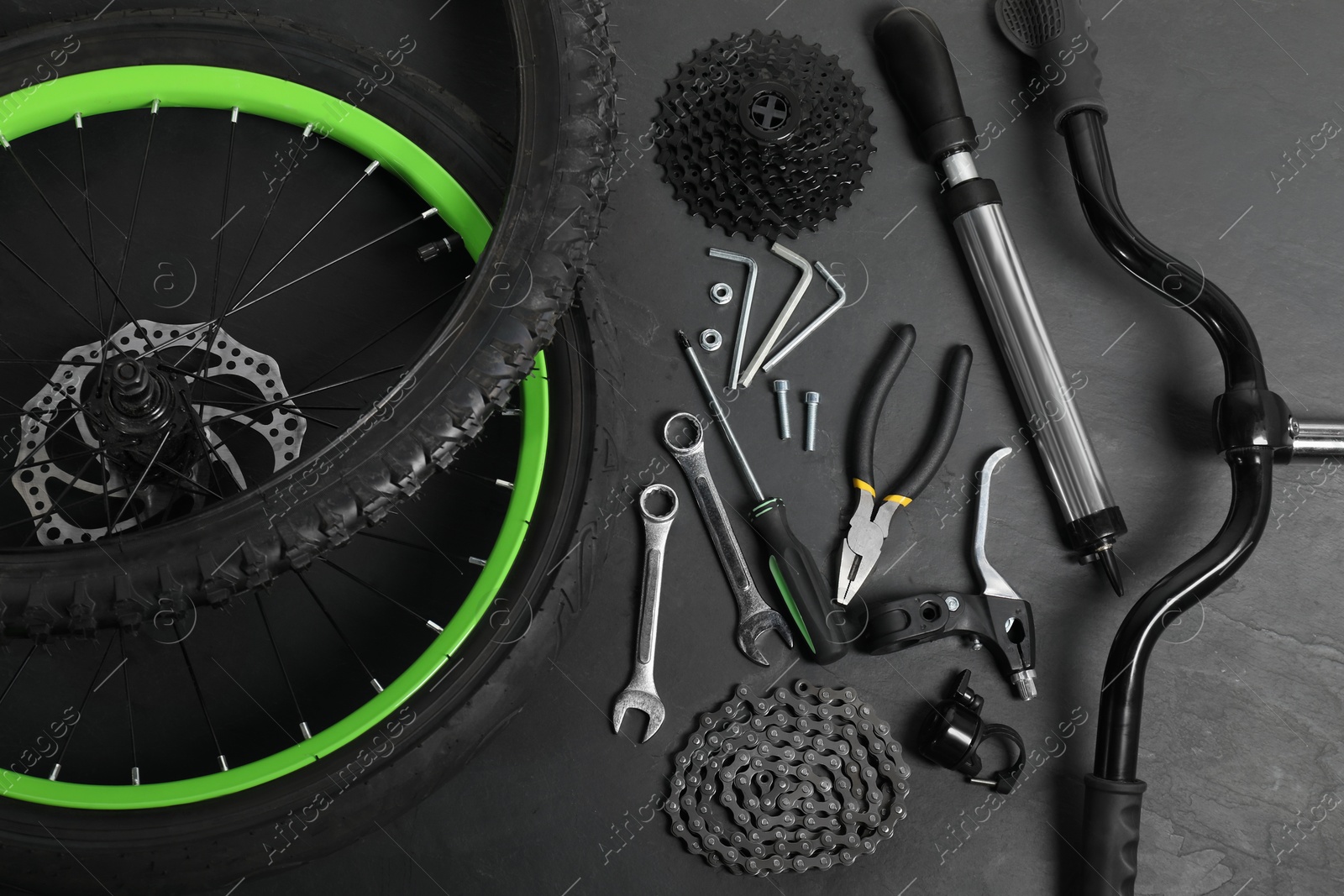 Photo of Parts of bicycle and tools on black background, above view