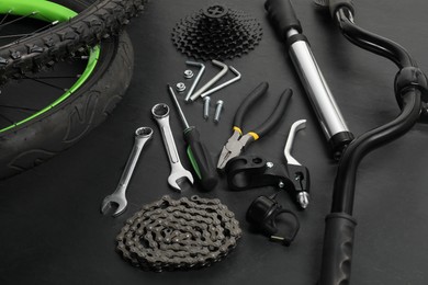 Photo of Parts of bicycle and tools on black background, closeup