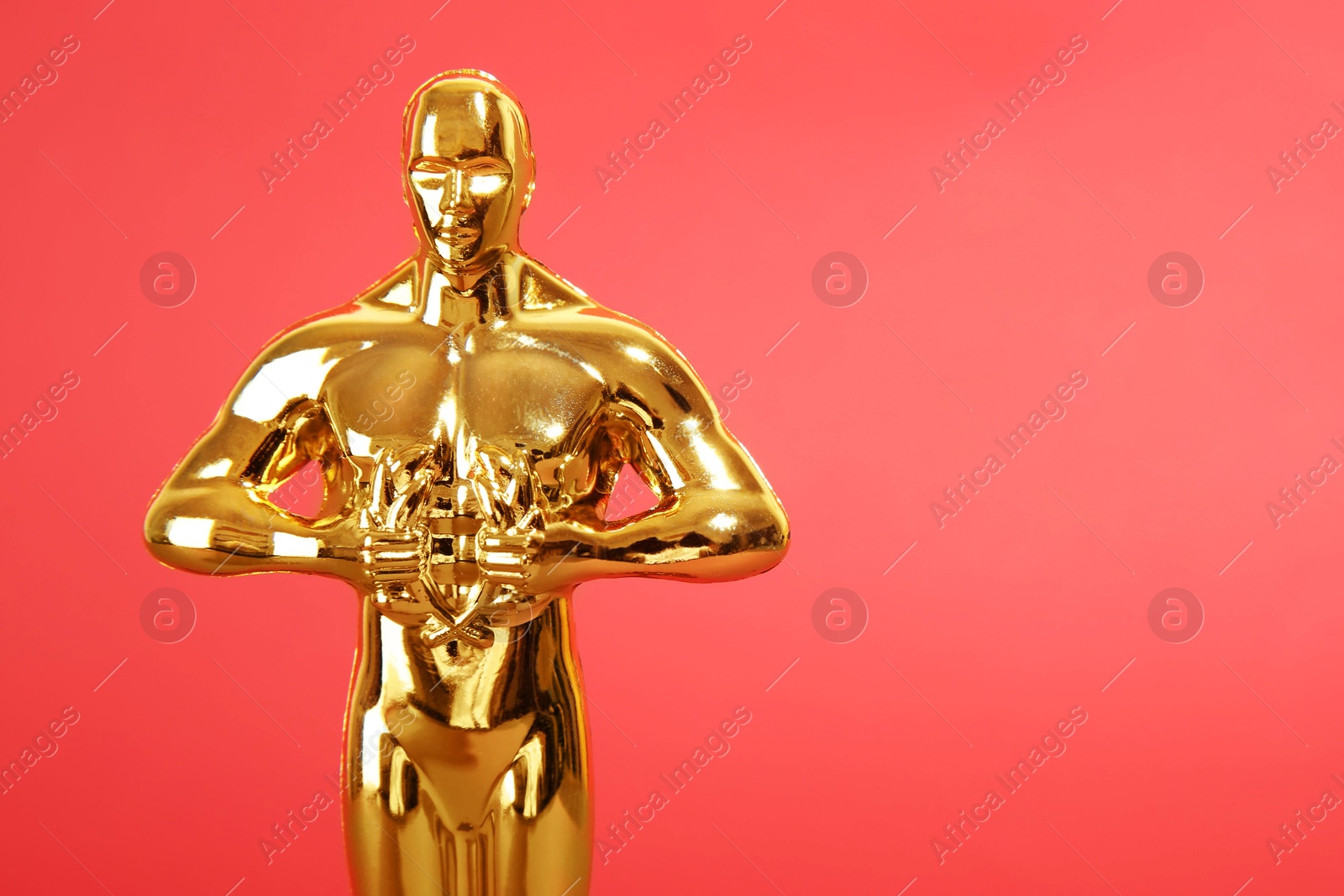 Photo of Golden trophy in shape of human figure on red background, closeup. Space for text