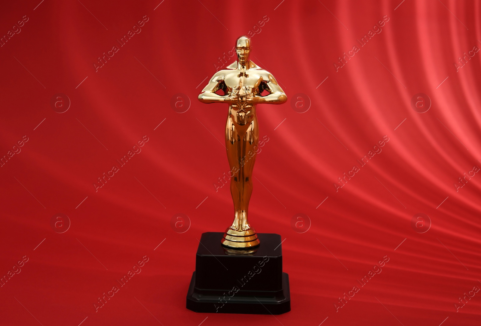 Photo of Golden trophy in shape of human figure on red background