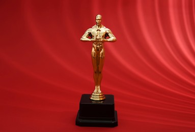 Photo of Golden trophy in shape of human figure on red background