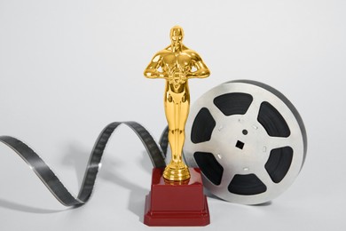 Photo of Golden trophy in shape of human figure and film reel on light background