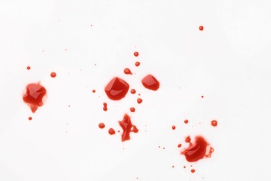 Photo of Stains of blood on white background, top view