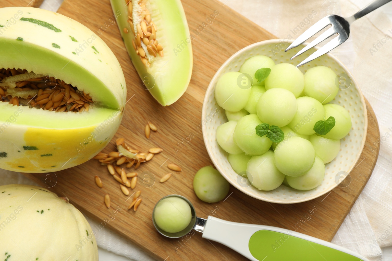 Photo of Melon balls in bowl and fresh fruit on table, top view