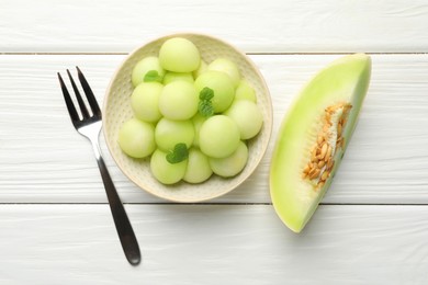 Photo of Melon balls in bowl and fresh fruit on wooden table, top view