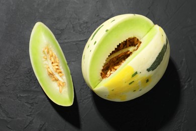 Photo of Fresh ripe honeydew melon on dark table, top view