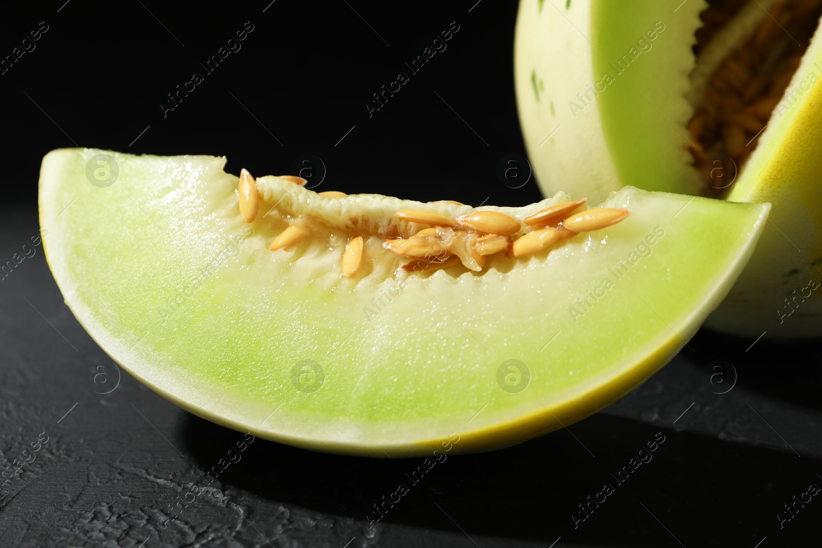 Photo of Fresh ripe honeydew melon on dark table, closeup