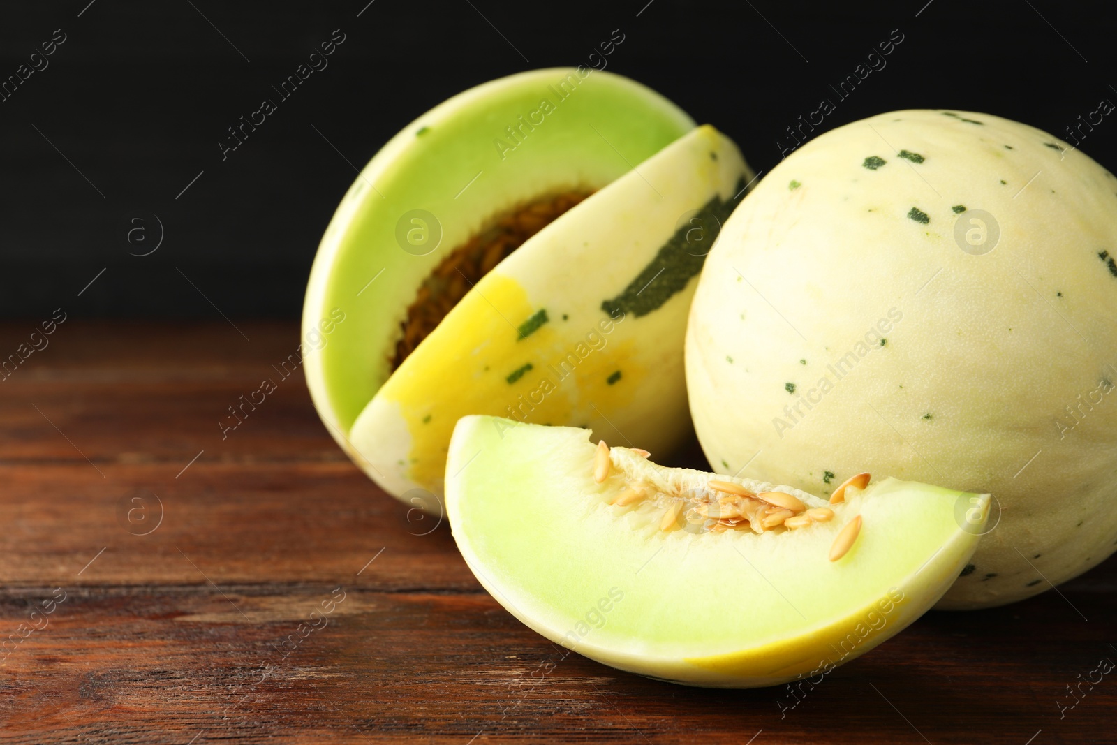 Photo of Fresh ripe honeydew melons on wooden table, space for text