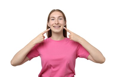 Photo of Smiling girl pointing at her braces on white background