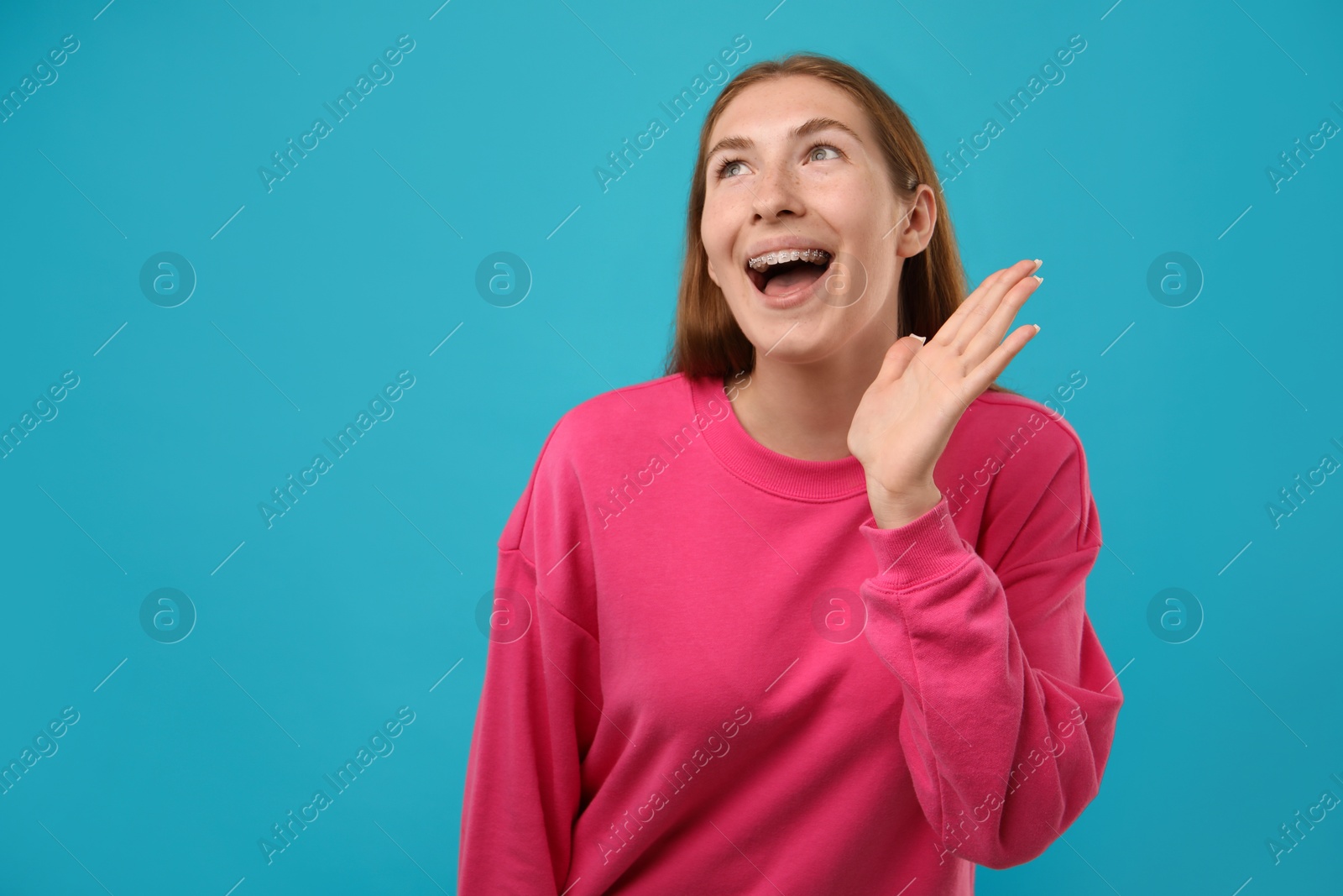 Photo of Smiling girl with braces on light blue background, space for text