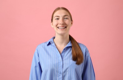 Photo of Smiling girl with braces on pink background