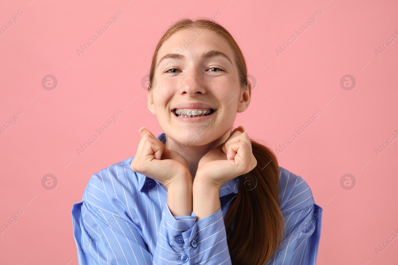 Photo of Smiling girl with braces on pink background