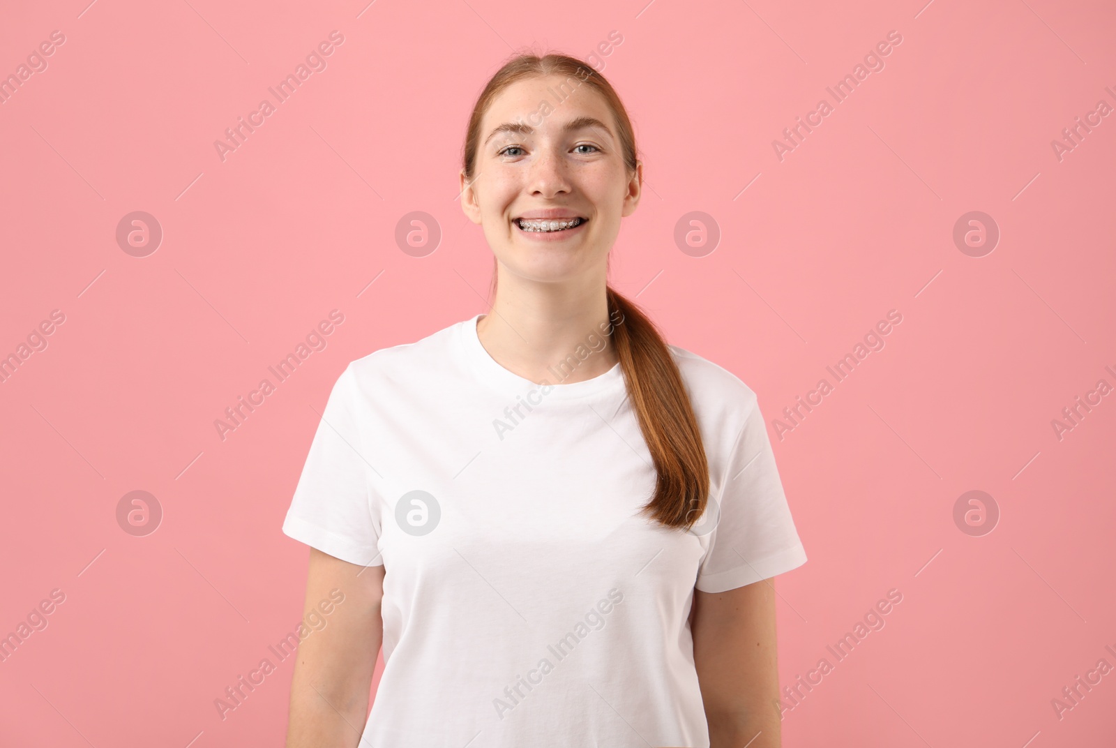 Photo of Smiling girl with braces on pink background