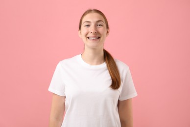 Photo of Smiling girl with braces on pink background