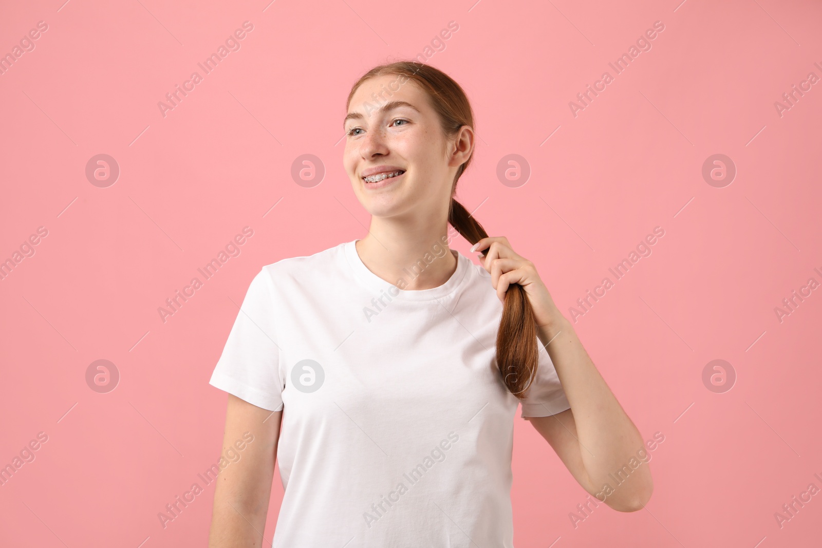 Photo of Smiling girl with braces on pink background