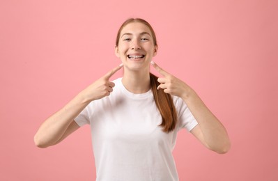 Photo of Girl pointing at her braces on pink background