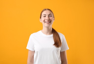 Photo of Smiling girl with braces on orange background