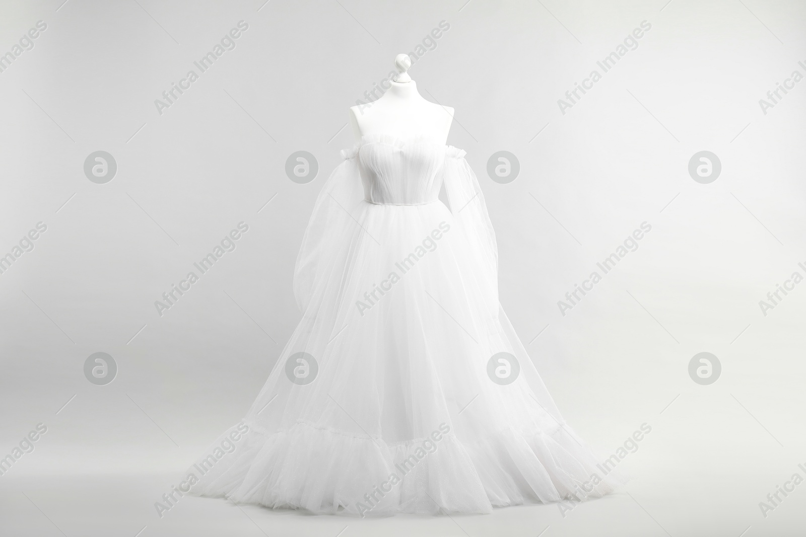 Photo of Mannequin with beautiful wedding dress and shoes on light grey background