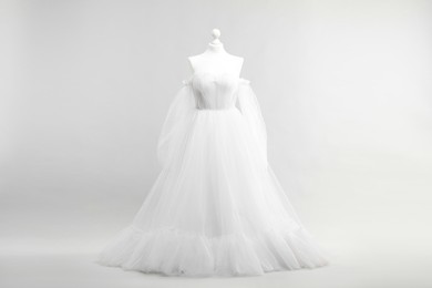 Photo of Mannequin with beautiful wedding dress and shoes on light grey background