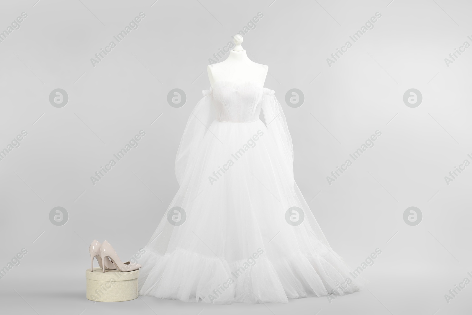 Photo of Mannequin with beautiful wedding dress and shoes on light grey background