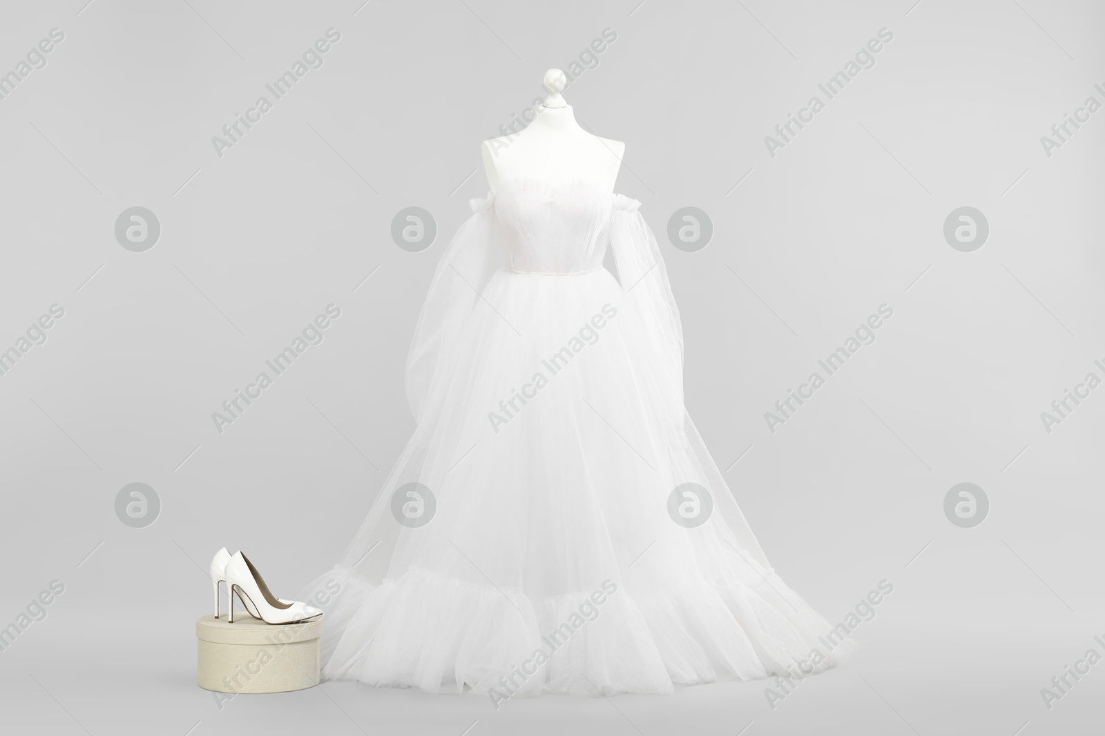 Photo of Mannequin with beautiful wedding dress and shoes on light grey background