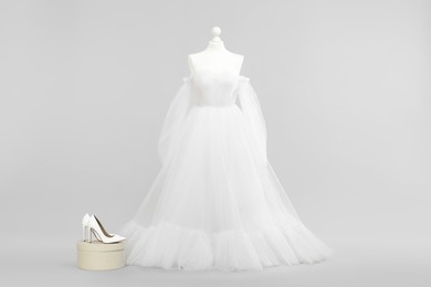 Photo of Mannequin with beautiful wedding dress and shoes on light grey background