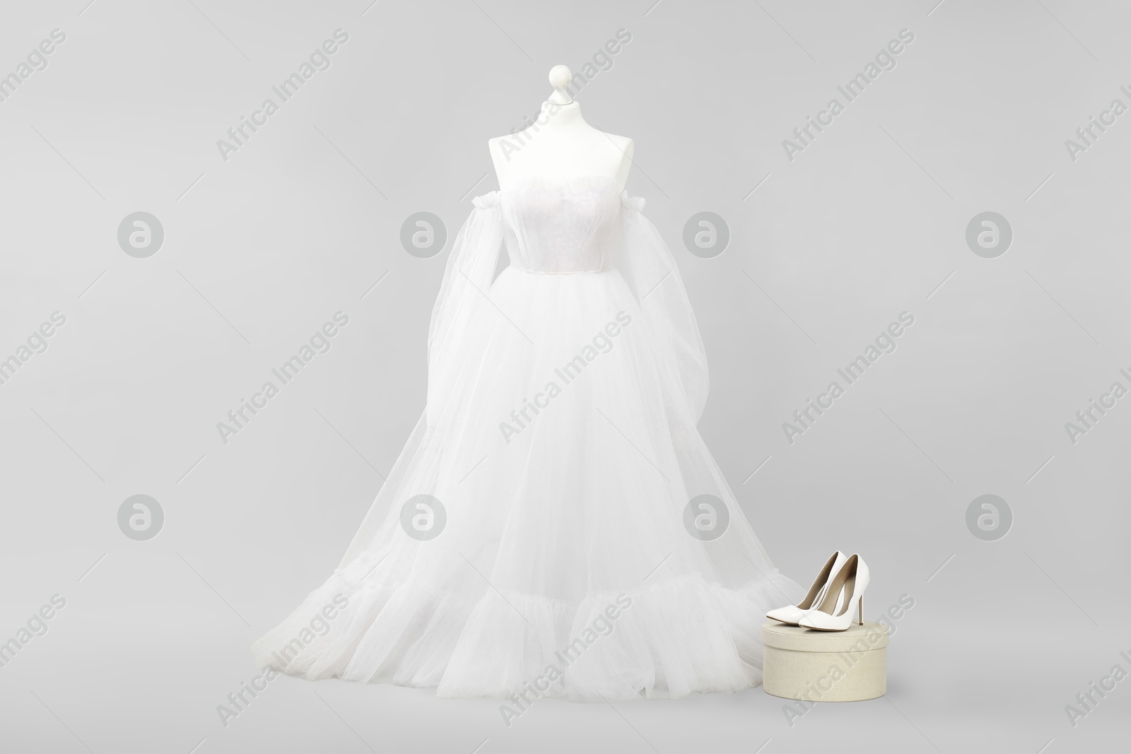 Photo of Mannequin with beautiful wedding dress and shoes on light grey background