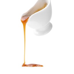 Tasty caramel sauce dripping from gravy boat on white background, closeup