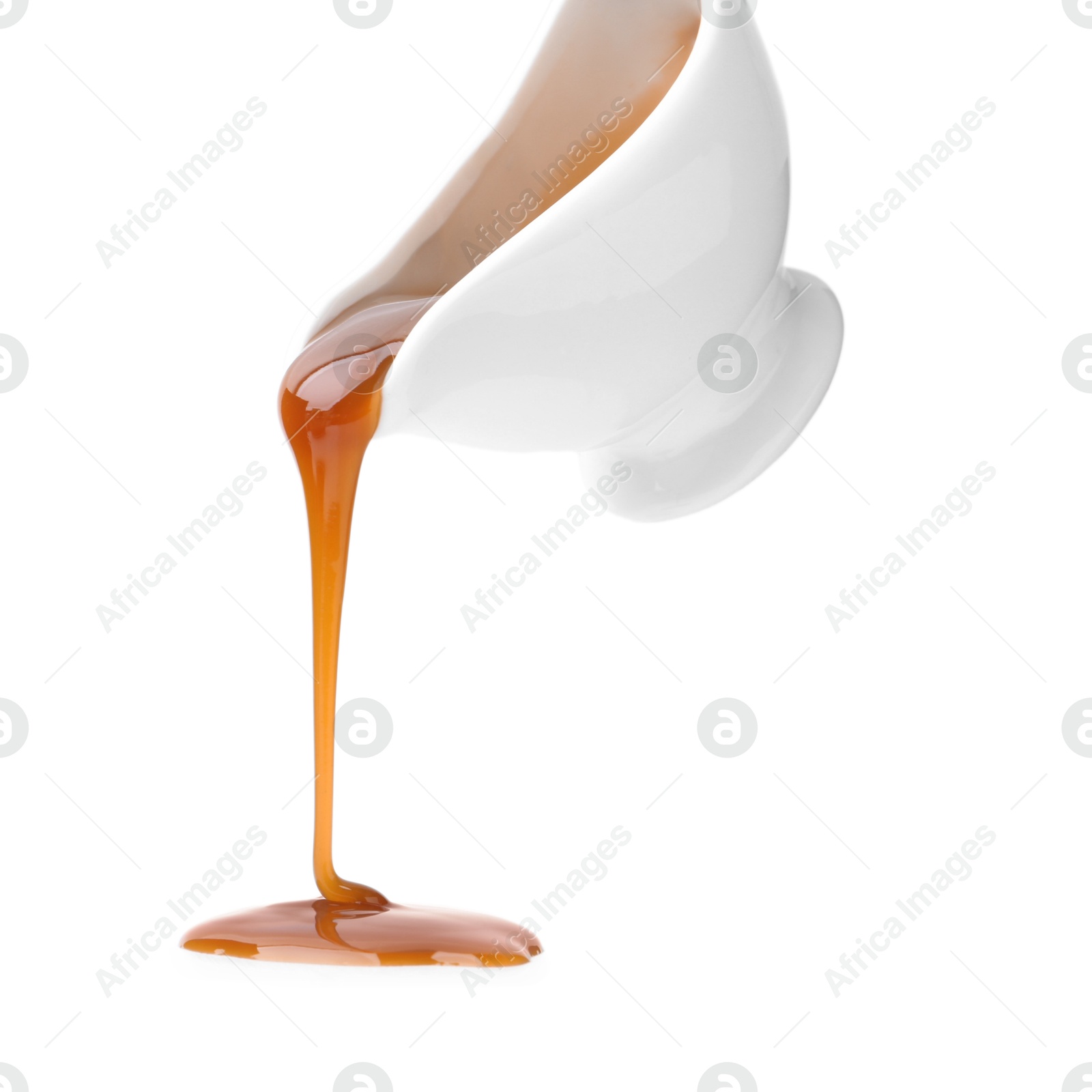 Photo of Tasty caramel sauce dripping from gravy boat on white background, closeup