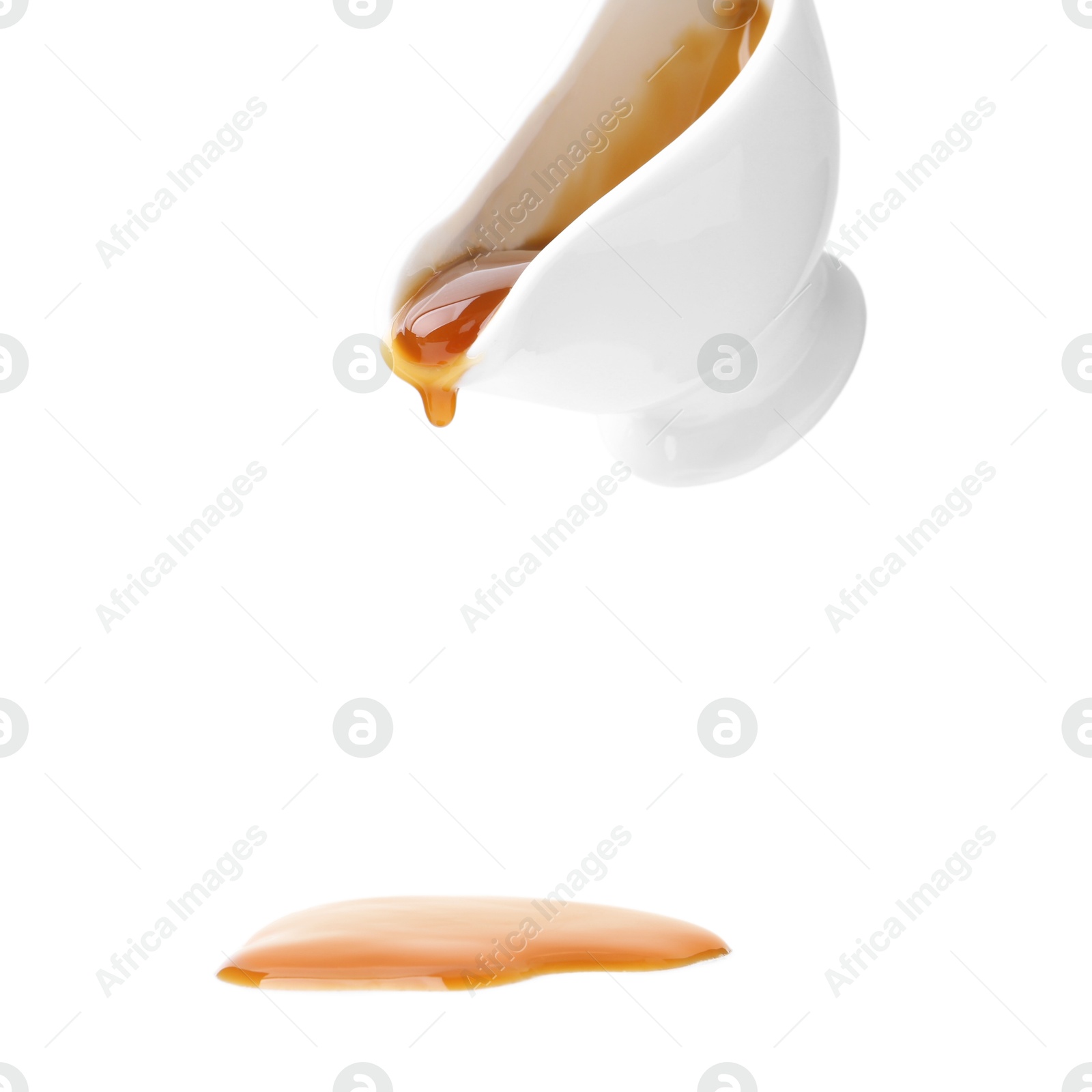 Photo of Tasty caramel sauce dripping from gravy boat on white background, closeup