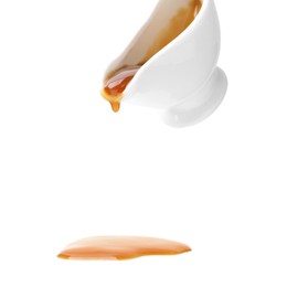 Photo of Tasty caramel sauce dripping from gravy boat on white background, closeup