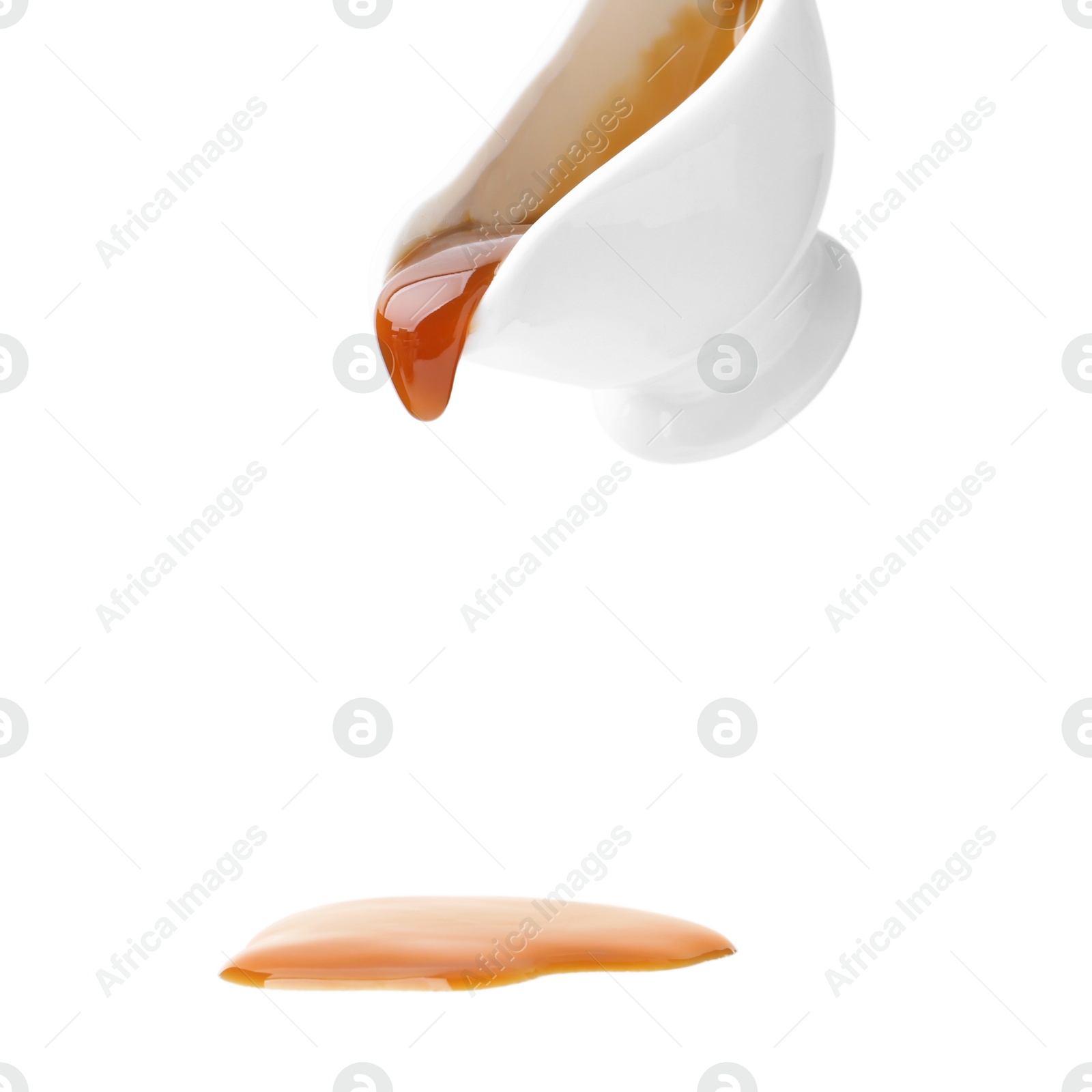 Photo of Tasty caramel sauce dripping from gravy boat on white background, closeup