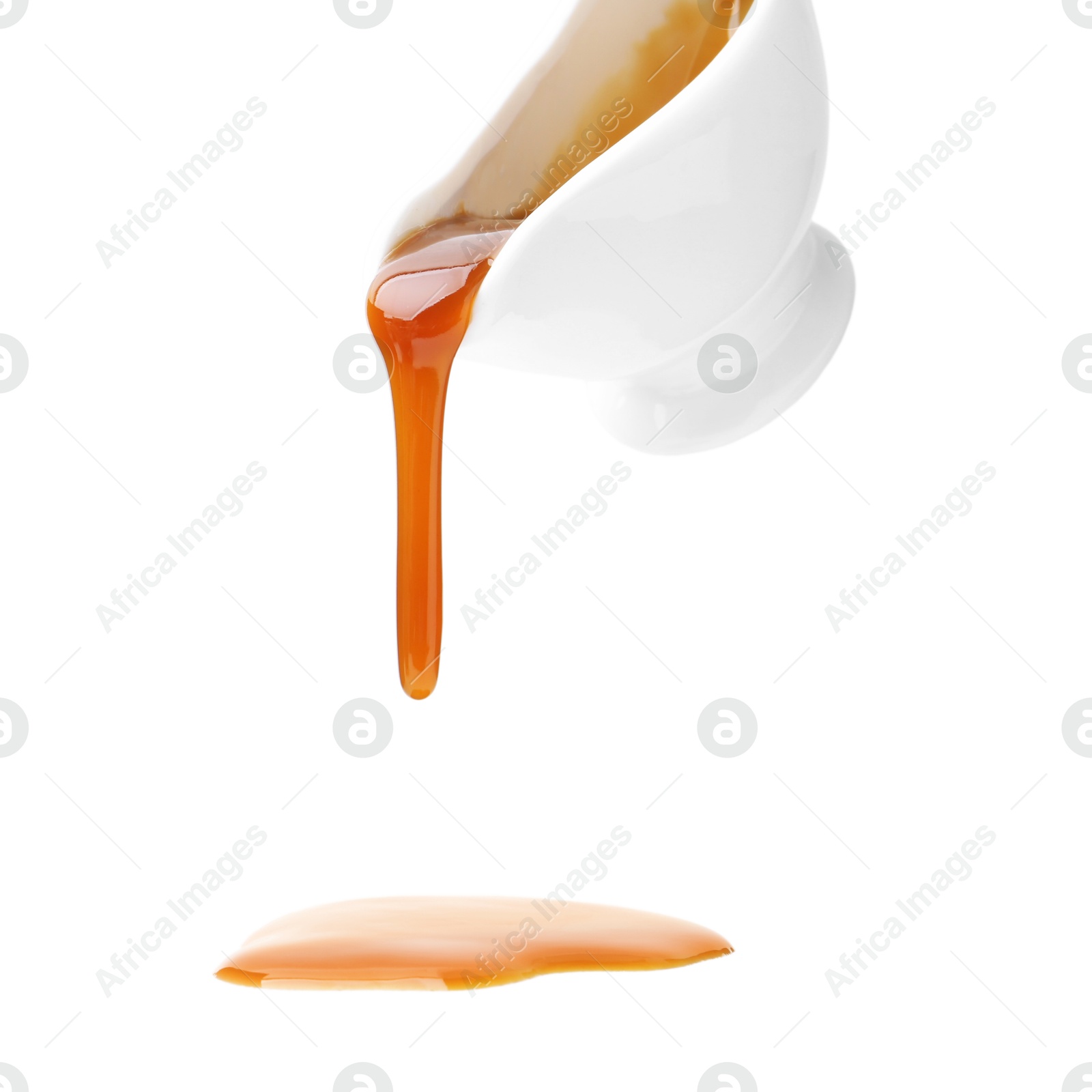 Photo of Tasty caramel sauce dripping from gravy boat on white background, closeup