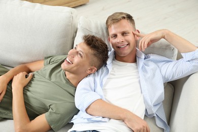 Happy brothers chilling on sofa at home