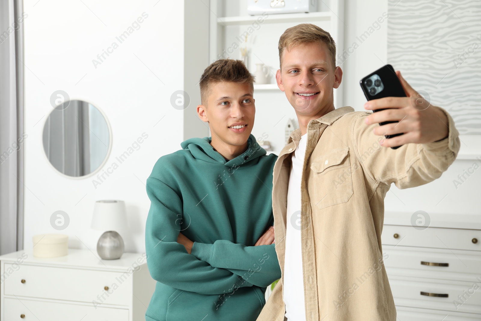 Photo of Happy brothers taking selfie at home. Space for text