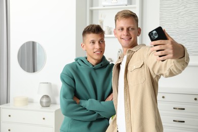 Photo of Happy brothers taking selfie at home. Space for text